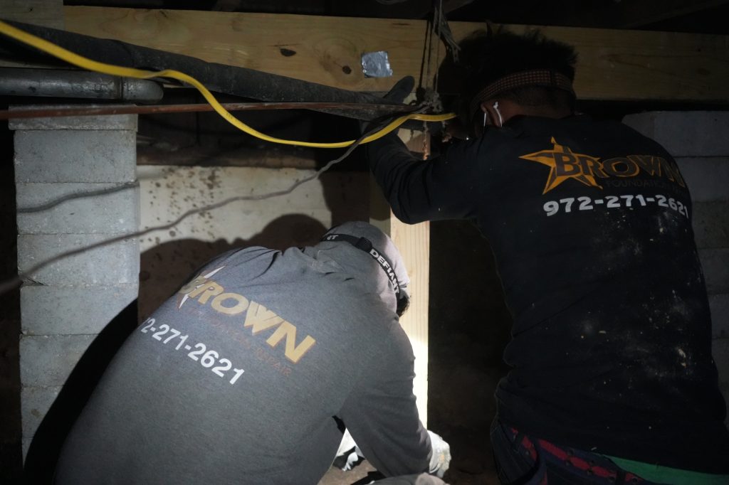 Brown Foundation crew working under a crawlspace to install humidifier