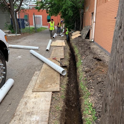 crew installing drainage and moisture barriers along exterior of brick property