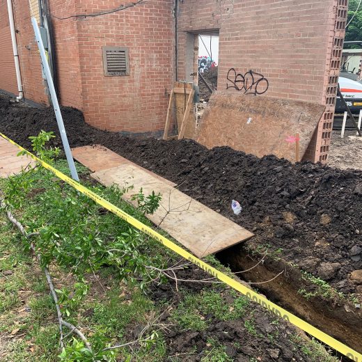 trench digging along commercial property for drainage project